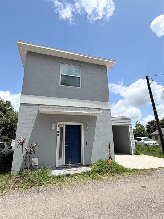 A two-story gray concrete block house with a blue front door and an attached carport — 3180 LINCOLN STREET, SANFORD, FL