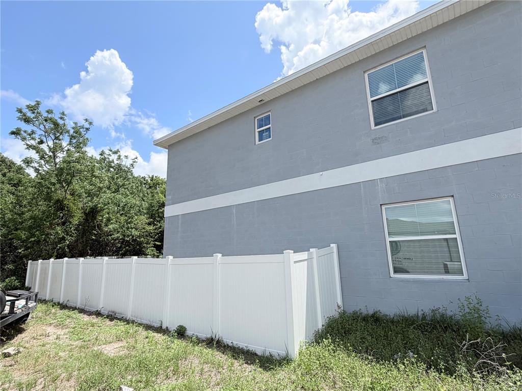 A gray two-story concrete block house stands behind a white vinyl privacy fence — 3180 LINCOLN STREET, SANFORD, FL