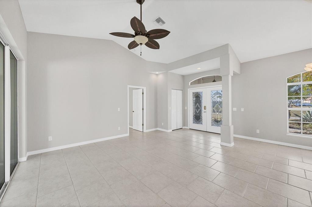 A spacious living room with light tile floors, a vaulted ceiling, and double front doors — 1236 NATRONA DRIVE, NORTH PORT, FL