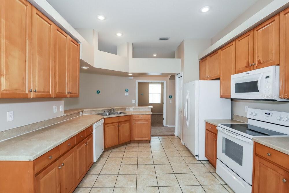 A kitchen with light wood cabinets, white appliances, and tan countertops over tiled floors — 513 9TH STREET NE, RUSKIN, FL