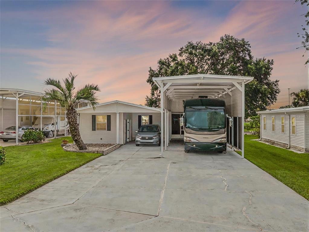 A mobile home with a large carport housing an RV and a car in the driveway — 5001 MOUNT OLIVE SHORES DRIVE, POLK CITY, FL