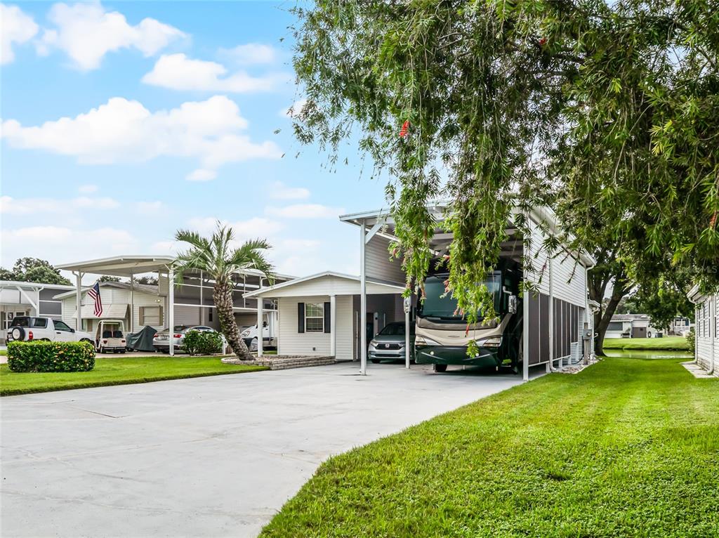 A house with a large carport housing a motorhome and a car on a driveway — 5001 MOUNT OLIVE SHORES DRIVE, POLK CITY, FL
