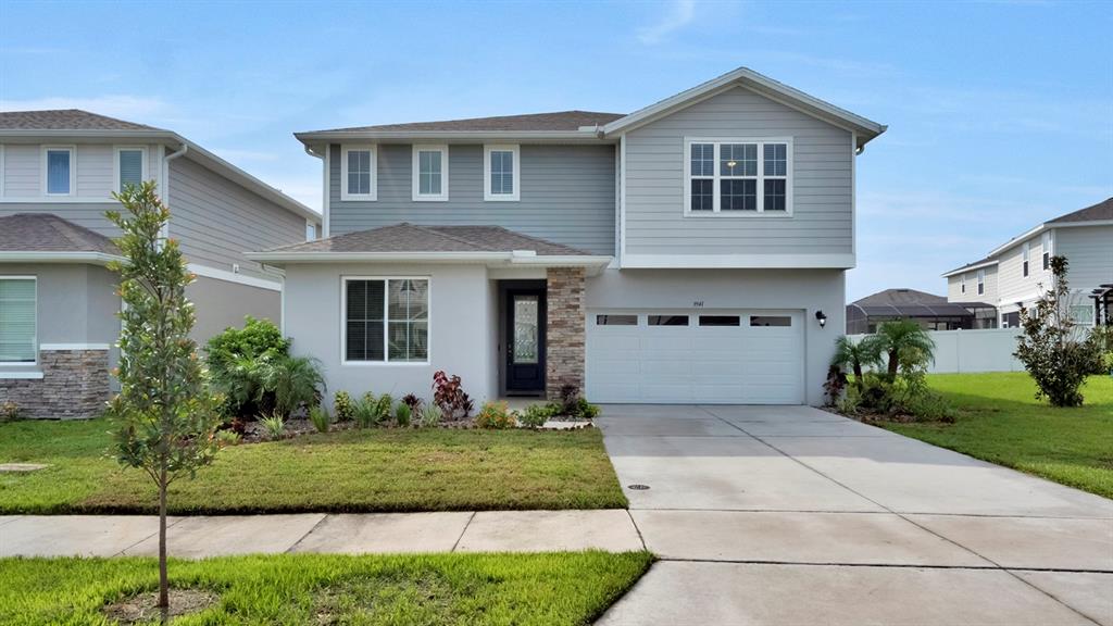 A two-story suburban house with gray siding, a stone-accented entryway, and a two-car garage — 3941 SOUTHERN VISTA LOOP, ST CLOUD, FL