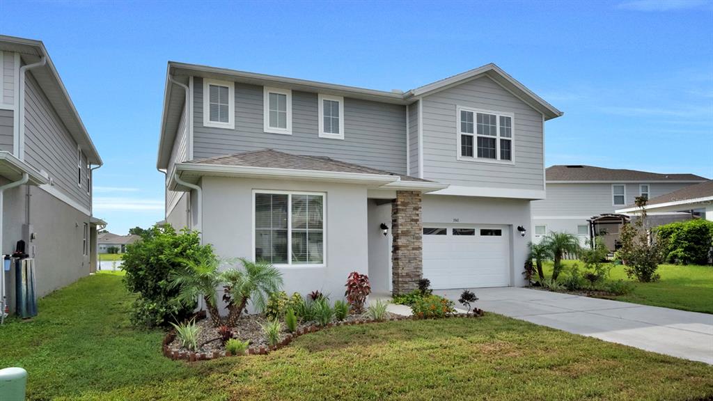 A two-story house with gray siding, a stone pillar, and a white garage door — 3941 SOUTHERN VISTA LOOP, ST CLOUD, FL