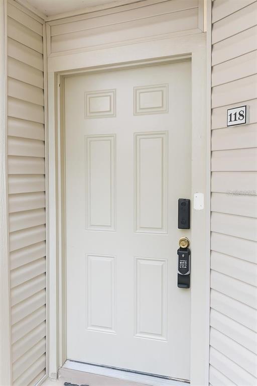 A beige six-panel front door with a digital keypad lock and unit number 118 — 1948 LAKE ATRIUMS CIRCLE UNIT 118, ORLANDO, FL