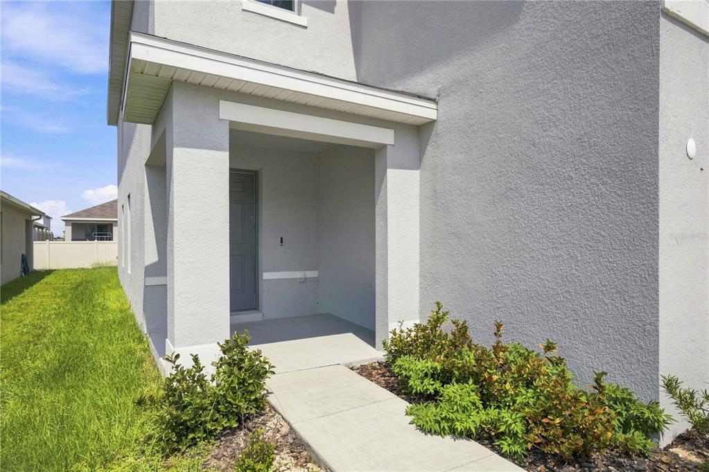A concrete walkway leads to the covered entryway of a gray stucco house — 8642 SW 46TH AVENUE, OCALA, FL
