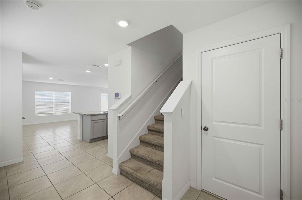 An interior view shows a carpeted staircase, a white door, and a tiled kitchen area — 8642 SW 46TH AVENUE, OCALA, FL