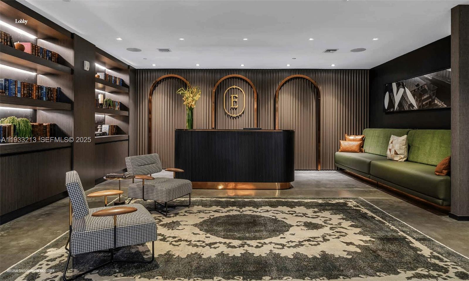 A modern lobby features a dark reception desk, green sofa, patterned rug, and built-in shelving — 398 NE 5th St # 1614, Miami FL 33132, MIAMI, FL
