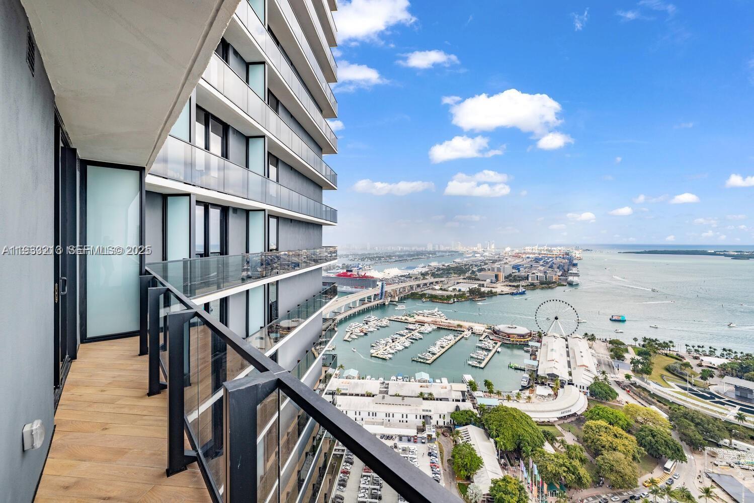 A high-rise balcony with wood-look flooring overlooks a harbor, marina, and city skyline — 398 NE 5th St # 1614, Miami FL 33132, MIAMI, FL