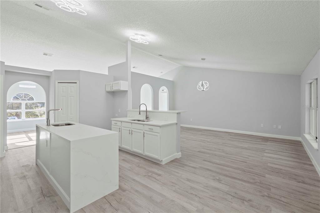 A kitchen with a white island and cabinets, light wood floors, and an open layout — 941 JAYHIL DRIVE, MINNEOLA, FL