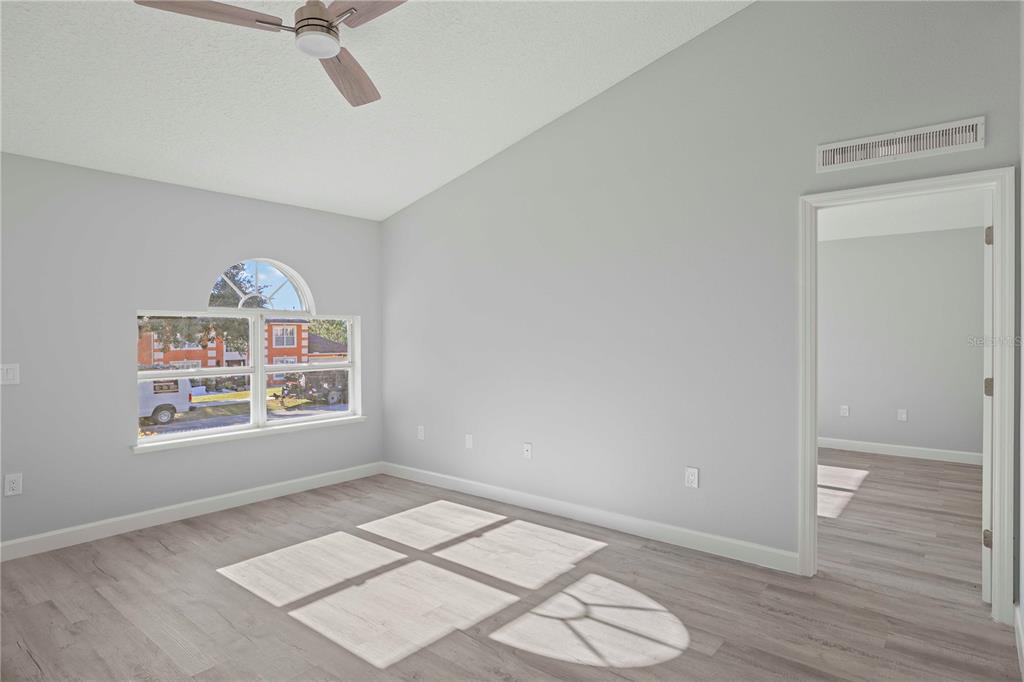 An empty bedroom with light gray walls, wood-look flooring, a ceiling fan, and arched window — 941 JAYHIL DRIVE, MINNEOLA, FL