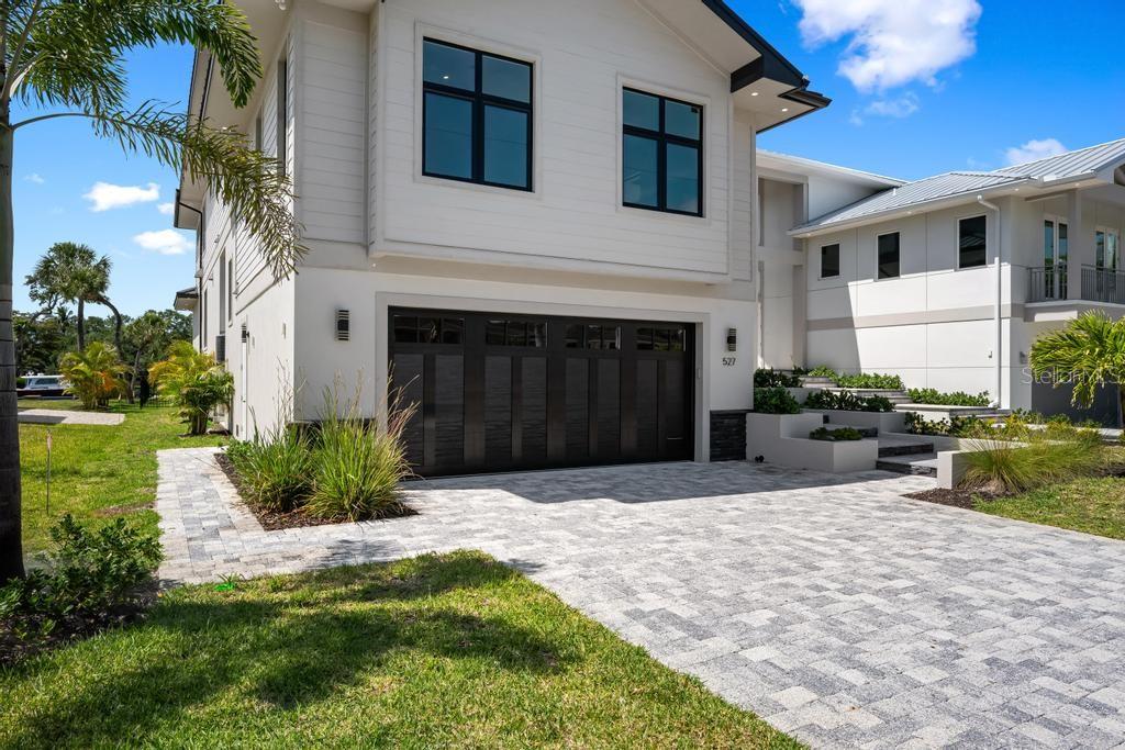 A two-story house with a dark garage door, white siding, and a paved driveway — 527 VENICE LANE, SARASOTA, FL