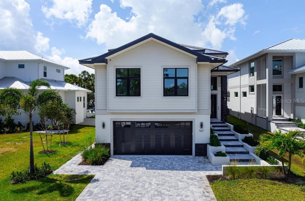 A modern two-story house features a dark garage door, white siding, and stone-paved driveway — 527 VENICE LANE, SARASOTA, FL