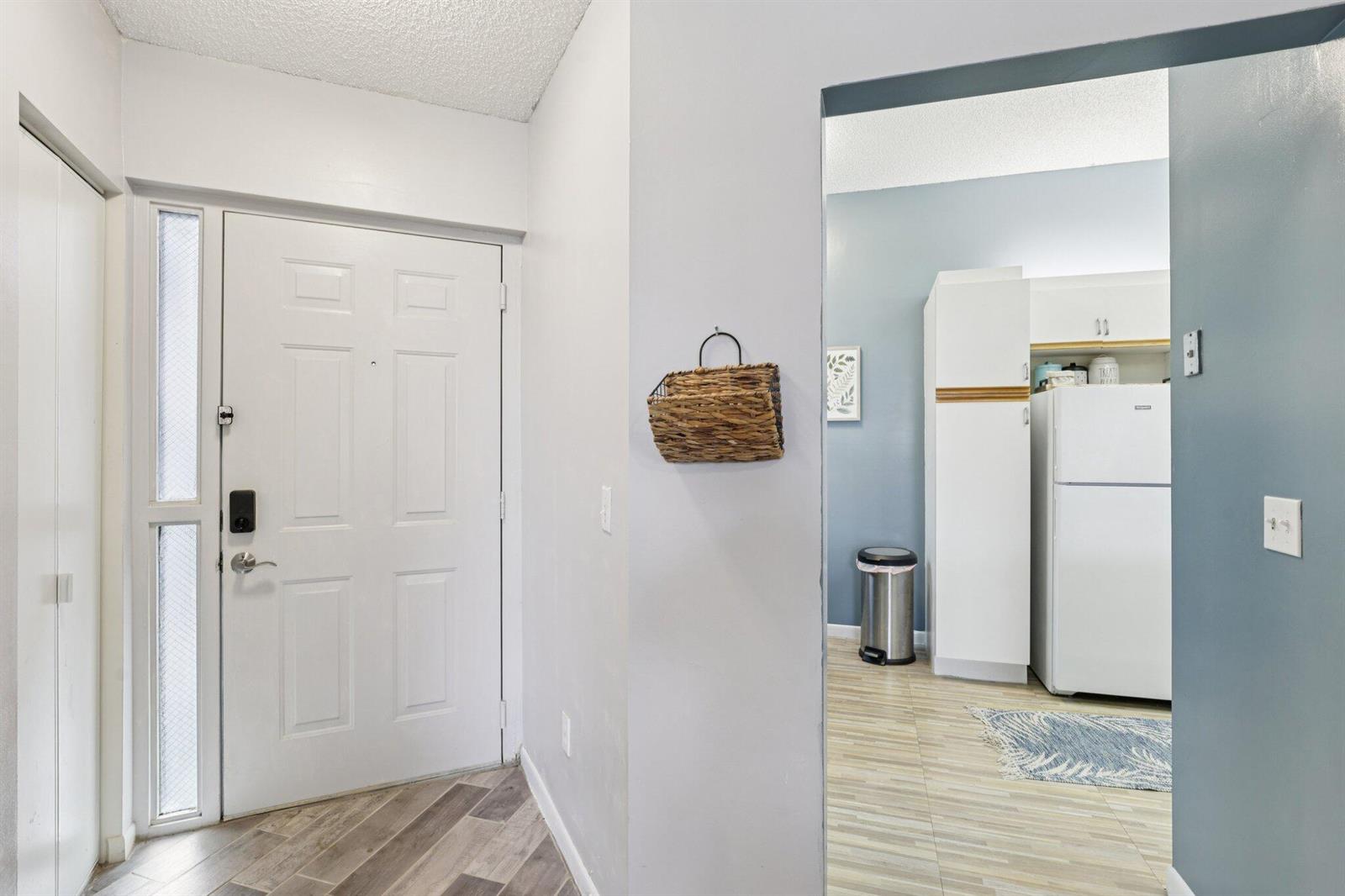 An entryway with a white door leads into a kitchen with light-colored flooring — 5394 Firenze Drive # O, Boynton Beach FL 33437, BOYNTON BEACH, FL
