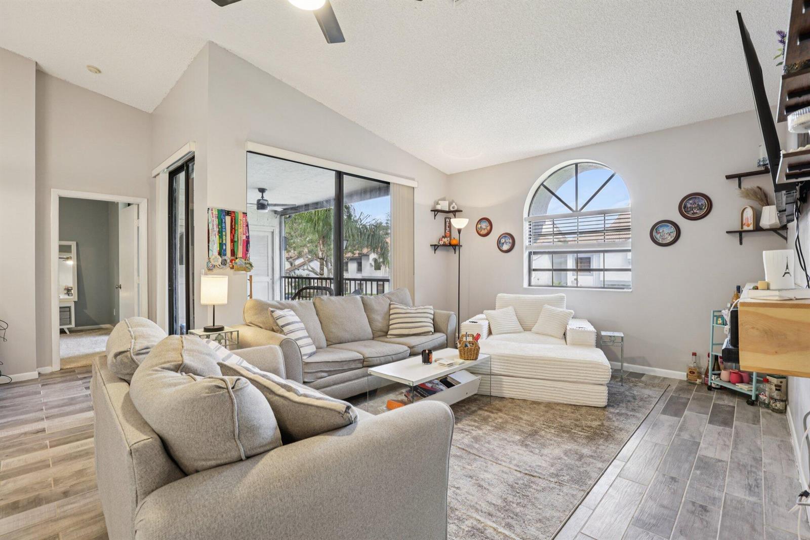 A living room features gray tile floors, a vaulted ceiling, and a large arched window — 5394 Firenze Drive # O, Boynton Beach FL 33437, BOYNTON BEACH, FL