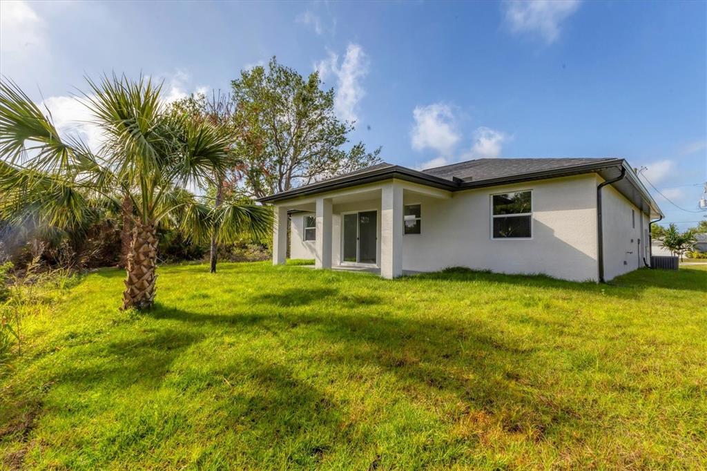 The exterior of a white house features a covered patio and a palm tree — 405 SUNSET ROAD N, ROTONDA WEST, FL