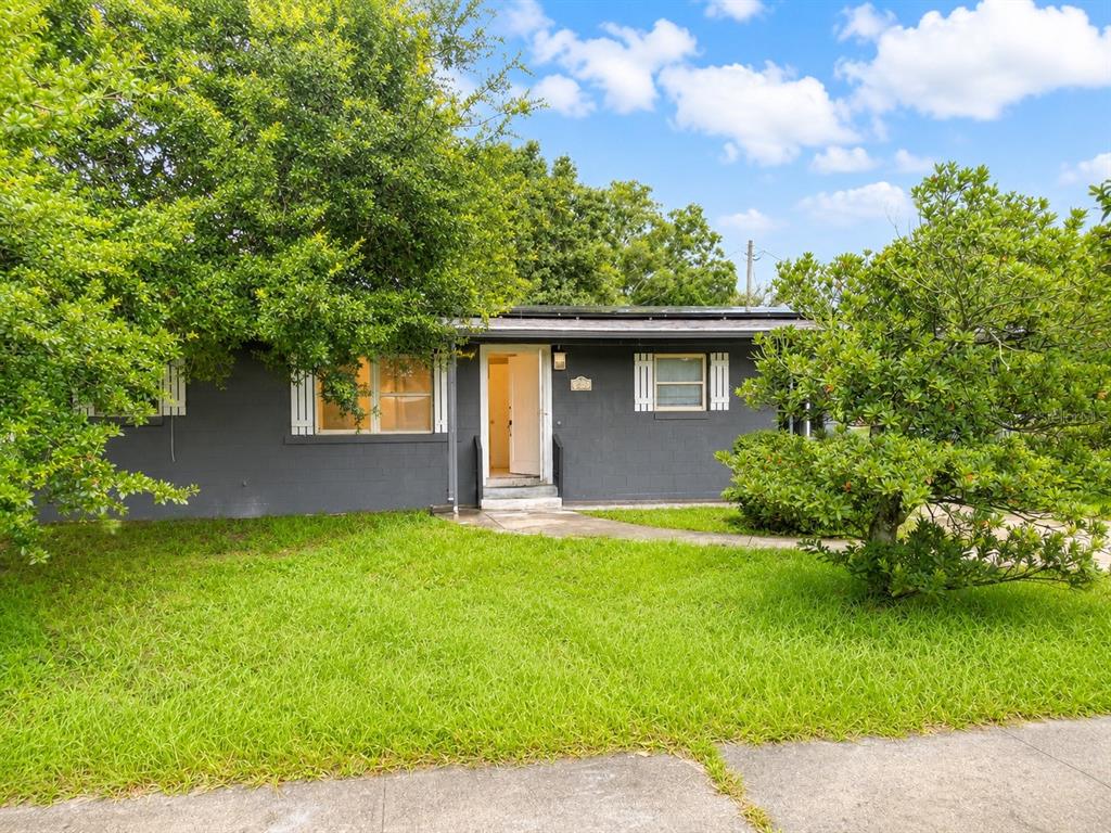 A single-story gray house with a front door, windows, and solar panels on the roof — 1243 AMAROS AVENUE, ORLANDO, FL