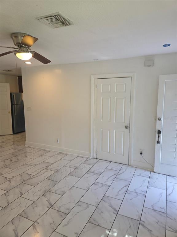 A room with white marble-patterned tile flooring, a ceiling fan, and two white interior doors — 1243 AMAROS AVENUE, ORLANDO, FL