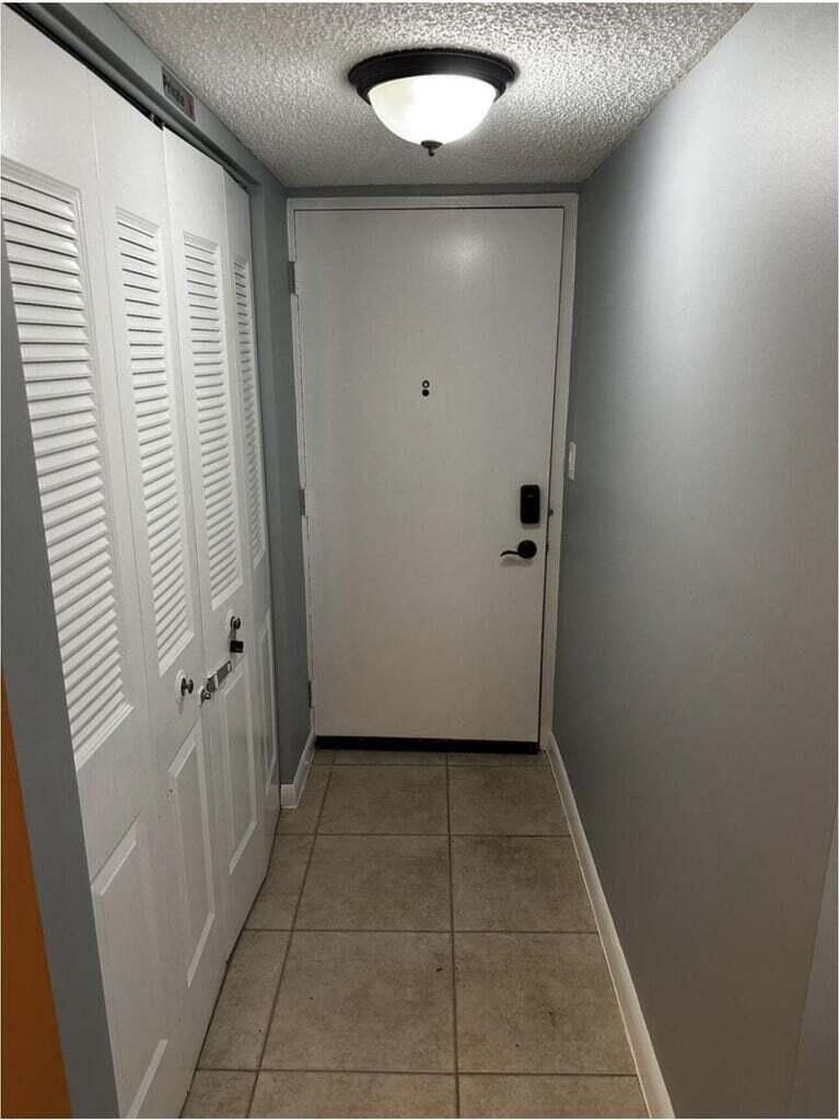 A narrow entryway features tiled flooring, a white door, and a white louvered closet door — 955 Dotterel Road # 2309, Delray Beach FL 33444, DELRAY BEACH, FL