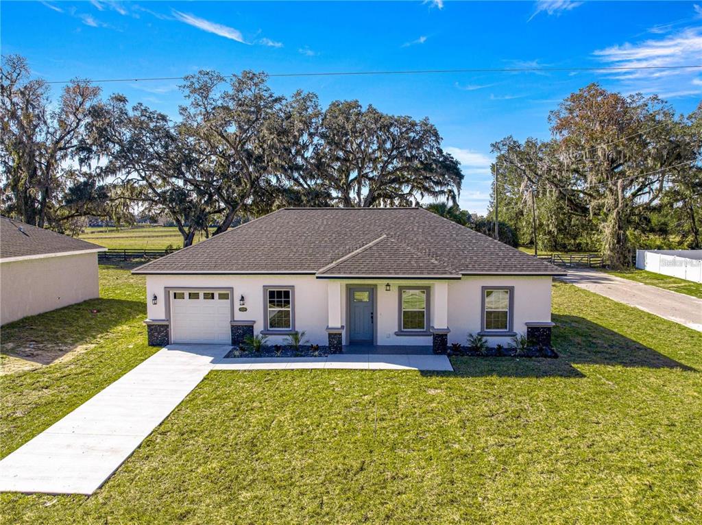 A single-story house with a white exterior, gray roof, and a concrete driveway — 15201 SE 61ST COURT, SUMMERFIELD, FL