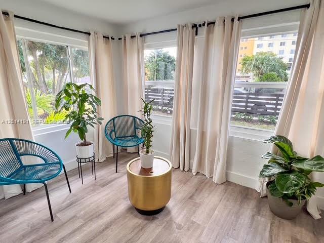 A sunroom features two teal chairs, a gold side table, and three potted plants — 1025 NW 55th St, Miami FL 33127, MIAMI, FL