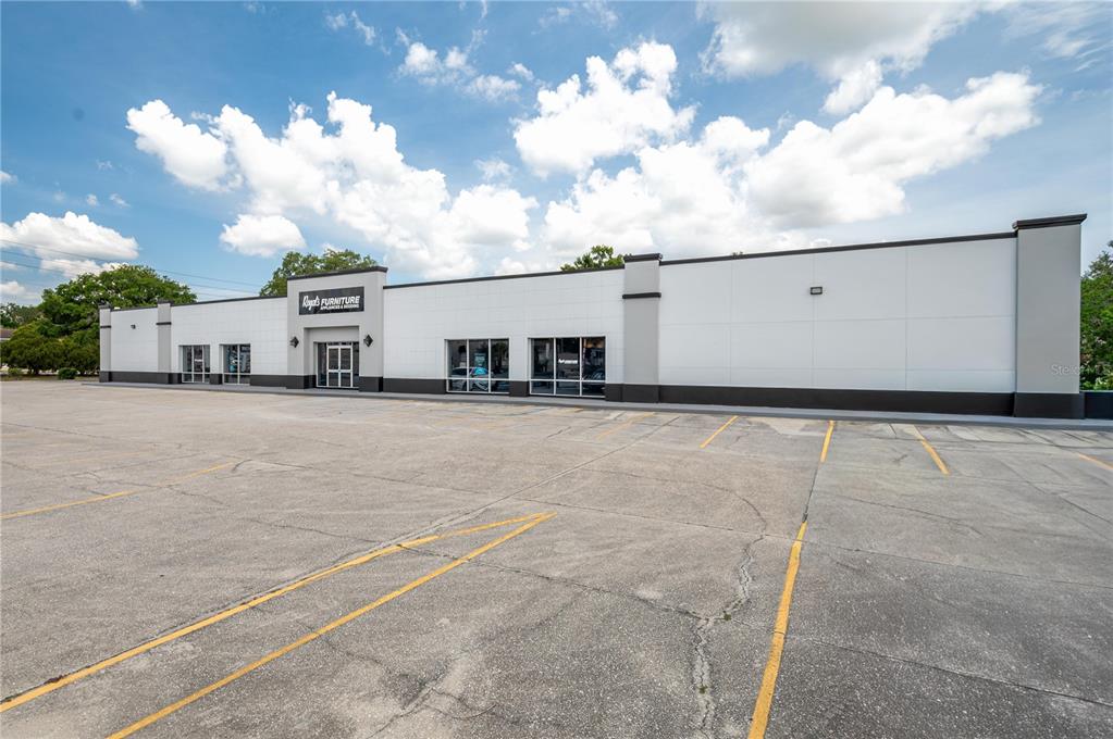 A single-story commercial building with a large parking lot under a blue sky — 126 STATE ROAD 60 W, LAKE WALES, FL