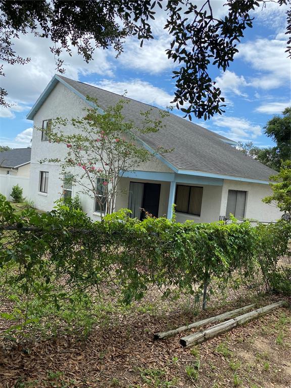 A two-story house with light-colored stucco siding and a gray shingled roof — 7415 RADIANT CIRCLE, ORLANDO, FL
