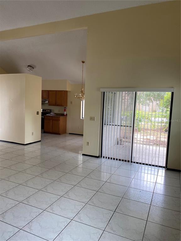 A tiled living area features a vaulted ceiling and sliding glass doors leading to a patio — 7415 RADIANT CIRCLE, ORLANDO, FL