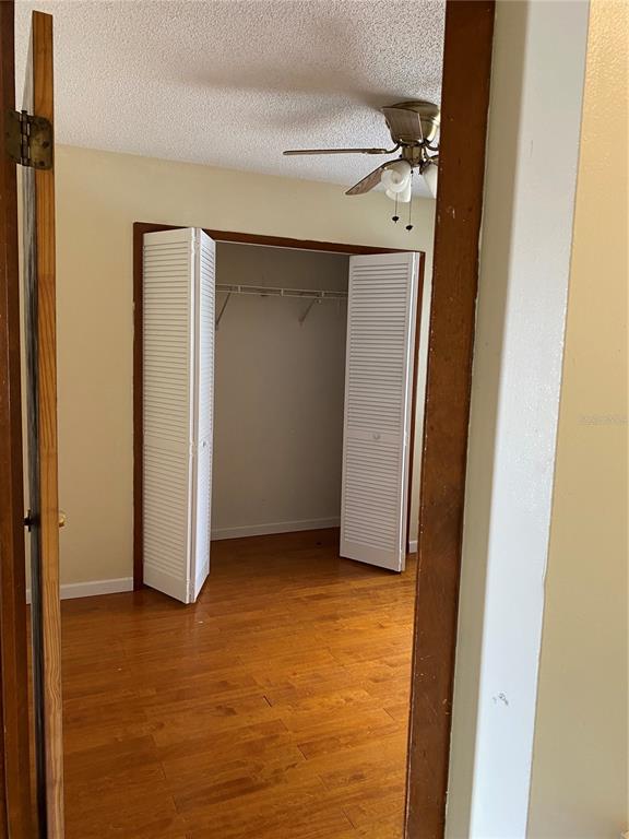 A bedroom with wood-look flooring, a ceiling fan, and a closet with white louvered doors — 7415 RADIANT CIRCLE, ORLANDO, FL