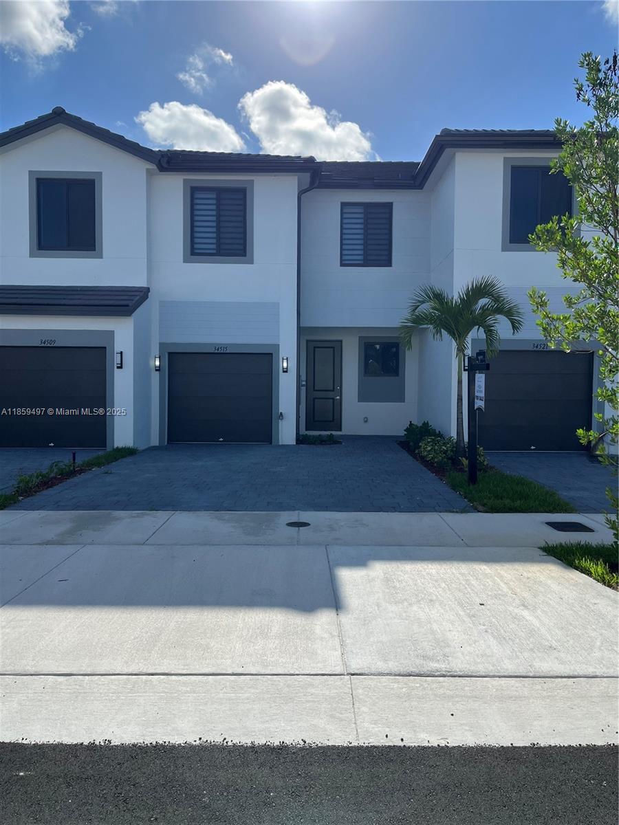 A row of three modern two-story townhomes features white facades, dark garage doors, and driveways — 34515 SW 191st Ct, Miami FL 33034, MIAMI, FL