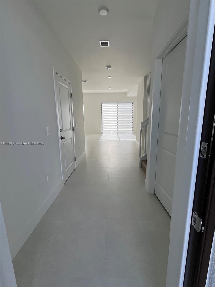 A bright hallway features white walls, tiled floors, recessed lighting, and doors on both sides — 34515 SW 191st Ct, Miami FL 33034, MIAMI, FL