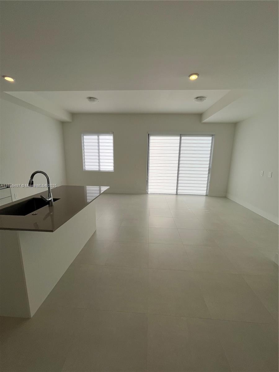 A modern kitchen with a brown countertop island opens into a bright, tiled living area — 34515 SW 191st Ct, Miami FL 33034, MIAMI, FL