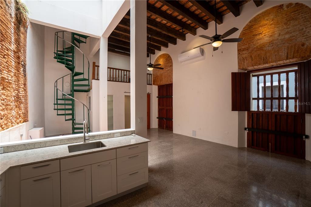 A kitchen with stone countertops overlooks a living area featuring a spiral staircase and beams — 8 DE LA CRUZ, SAN JUAN, PR