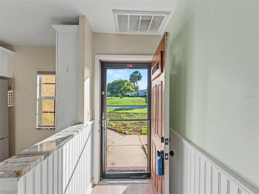 An open front door reveals a view of a grassy lawn and trees outside — 11430 CARRIAGE HILL DRIVE UNIT 4, PORT RICHEY, FL