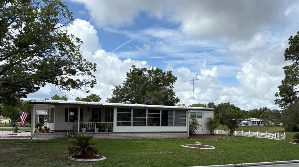 A single-story manufactured home with a screened-in porch sits on a grassy lot — 7363 BROOKRIDGE CENTRAL BOULEVARD, BROOKSVILLE, FL
