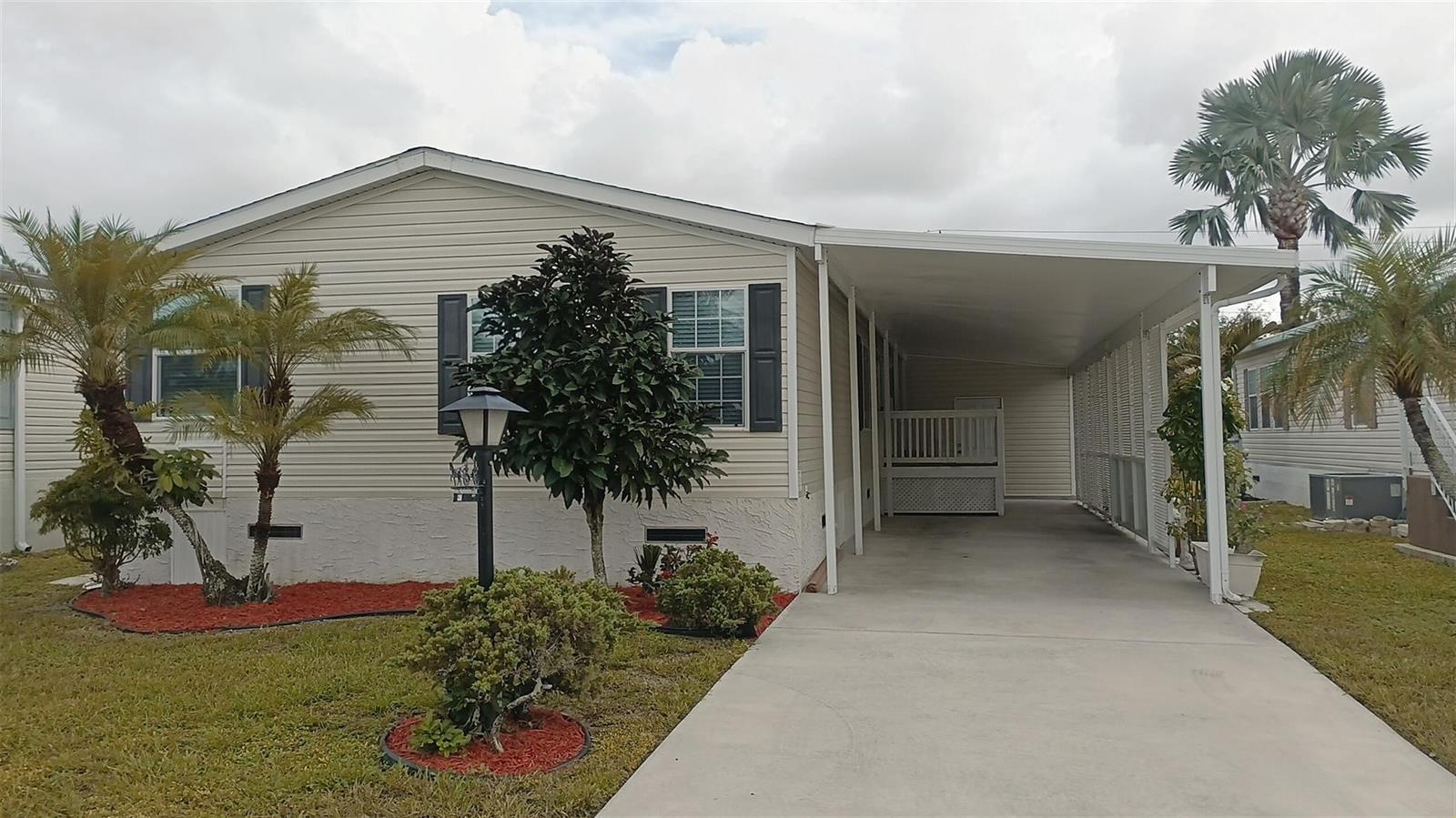 A single-story manufactured home with light siding, a concrete driveway, and a covered carport — 8204 South Street, Boca Raton FL 33433, BOCA RATON, FL