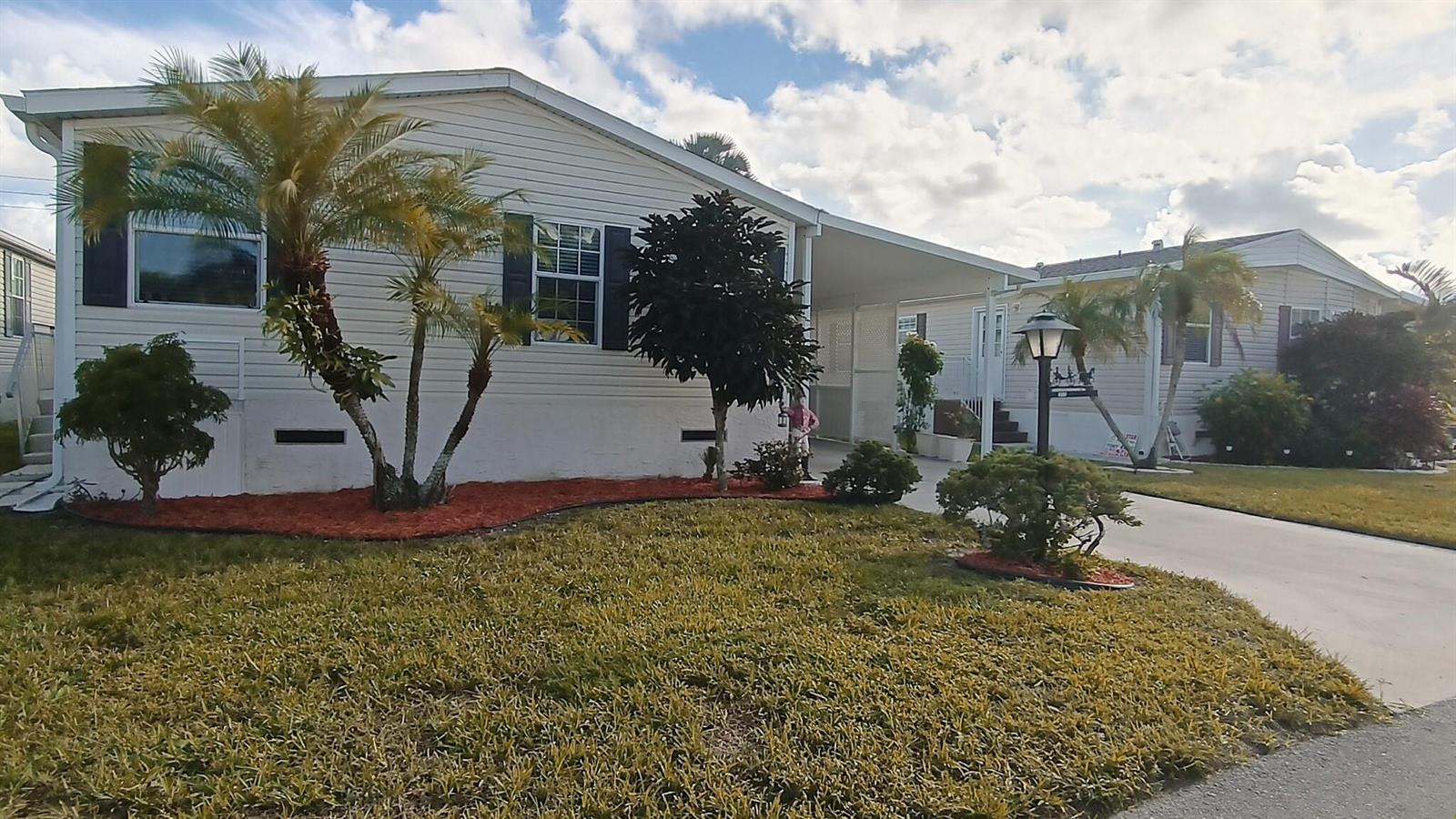 A single-story manufactured home with a carport, palm trees, and a landscaped front yard — 8204 South Street, Boca Raton FL 33433, BOCA RATON, FL