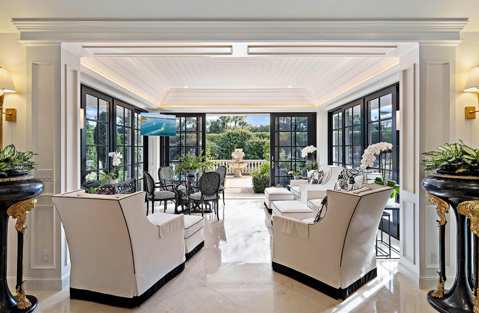 A sunroom features white armchairs, a dining set, and large glass doors opening to a patio — 11818 Lost Tree Way, North Palm Beach FL 33408, NORTH PALM BEACH, FL