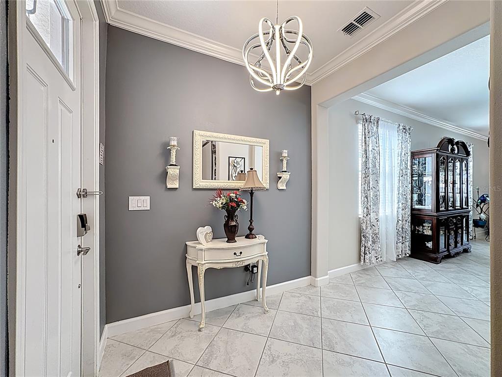 A gray-walled entryway features a white console table, a mirror, and a modern chandelier — 16815 WHISPER ELM STREET, WIMAUMA, FL