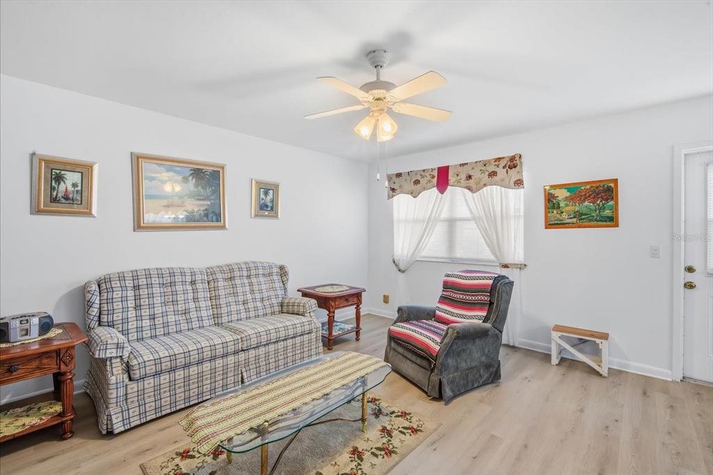 A living room features a plaid sofa, a recliner, a coffee table, and a ceiling fan — 202 BEDFORD STREET UNIT 49, SUN CITY CENTER, FL