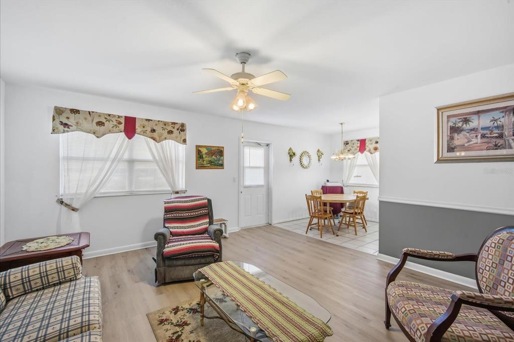 A living room with light wood flooring, a ceiling fan, and an adjacent dining area — 202 BEDFORD STREET UNIT 49, SUN CITY CENTER, FL