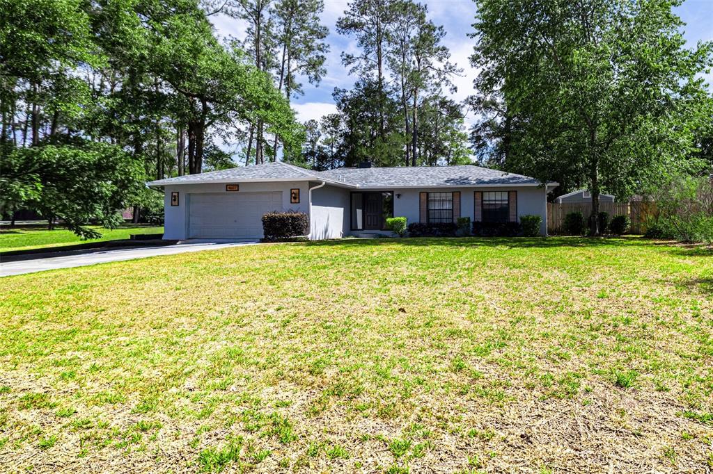 A single-story gray house with a two-car garage sits on a large, grassy lot — 4607 NW 31ST AVENUE, GAINESVILLE, FL