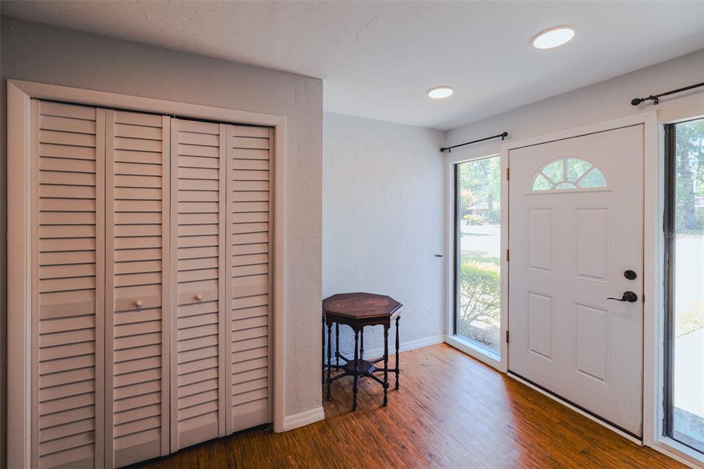 An entryway features wood flooring, a louvered closet, a small wooden table, and a front door — 4607 NW 31ST AVENUE, GAINESVILLE, FL