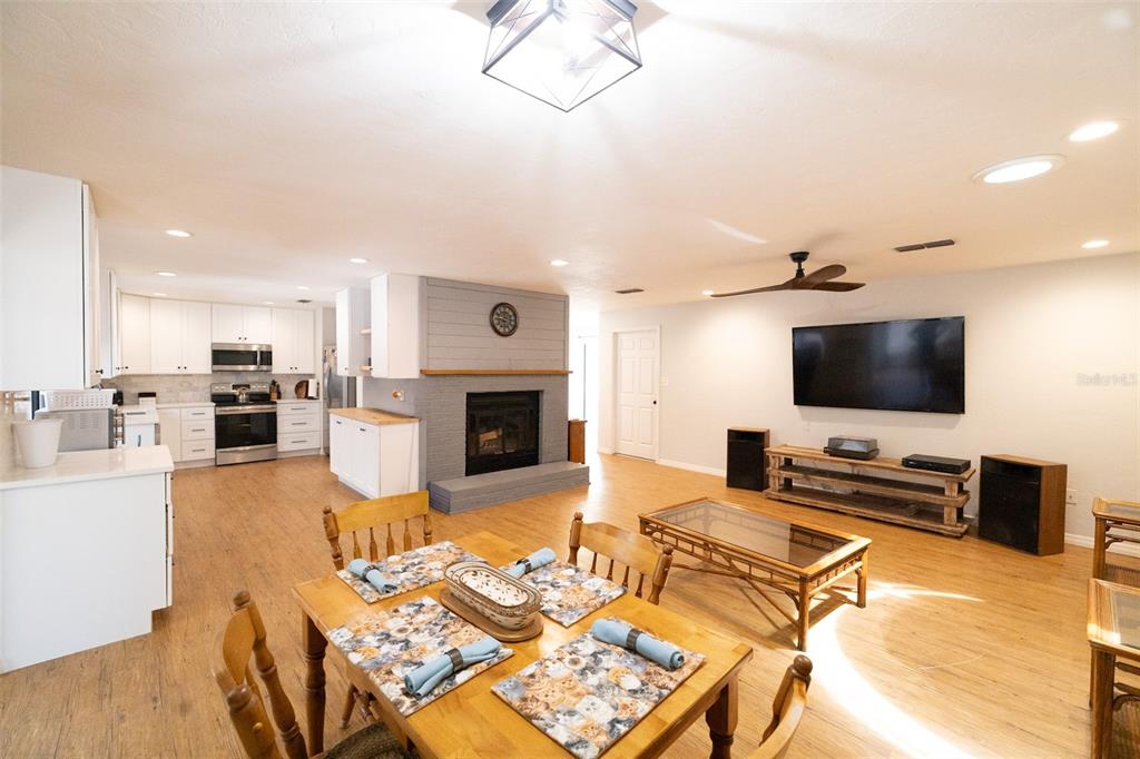 An open-concept living and dining area features a gray brick fireplace and white kitchen cabinetry — 4607 NW 31ST AVENUE, GAINESVILLE, FL