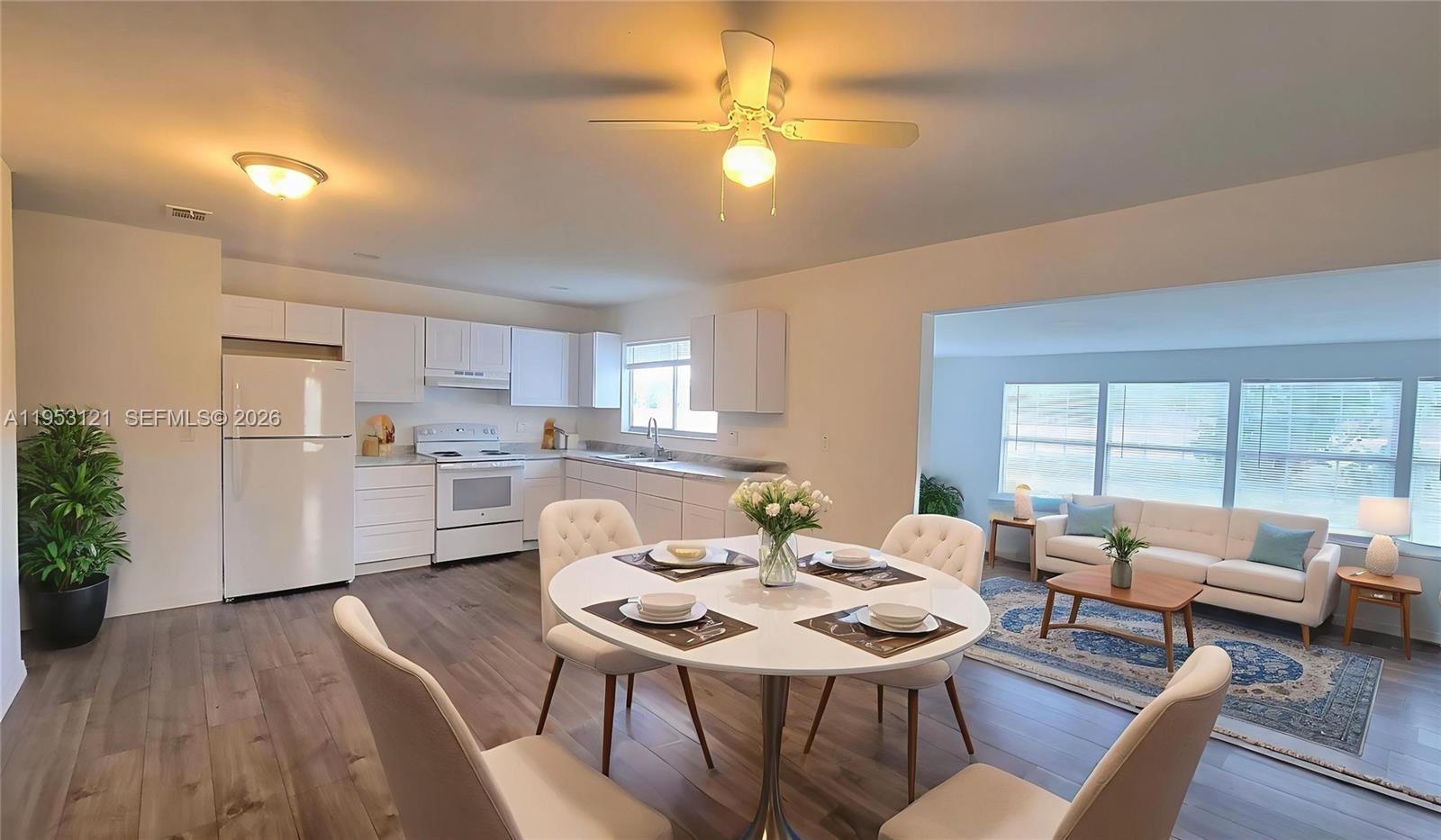 An open-concept kitchen and dining area features white cabinetry, a round table, and wood flooring — 4008 Rye Ct, La Belle FL 33935, LA BELLE, FL