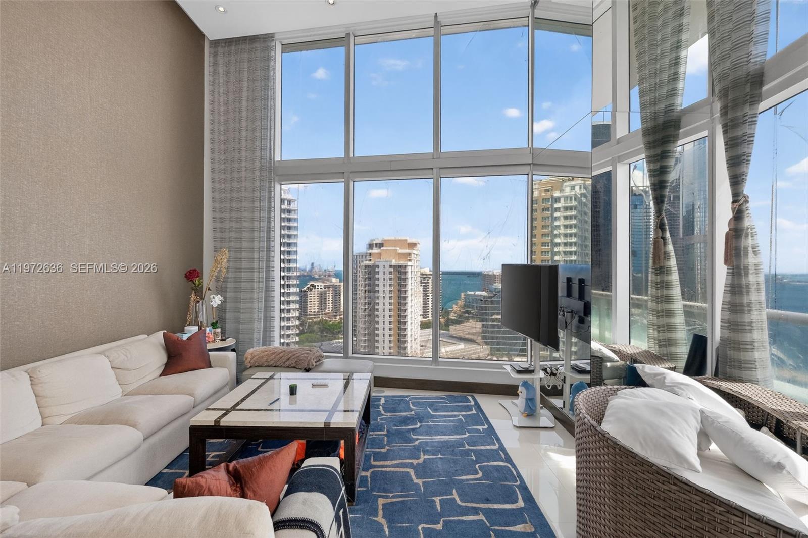 A living room features floor-to-ceiling windows with city and ocean views, a sofa, and rug — 495 Brickell avenue # 2201, Miami FL 33131, MIAMI, FL