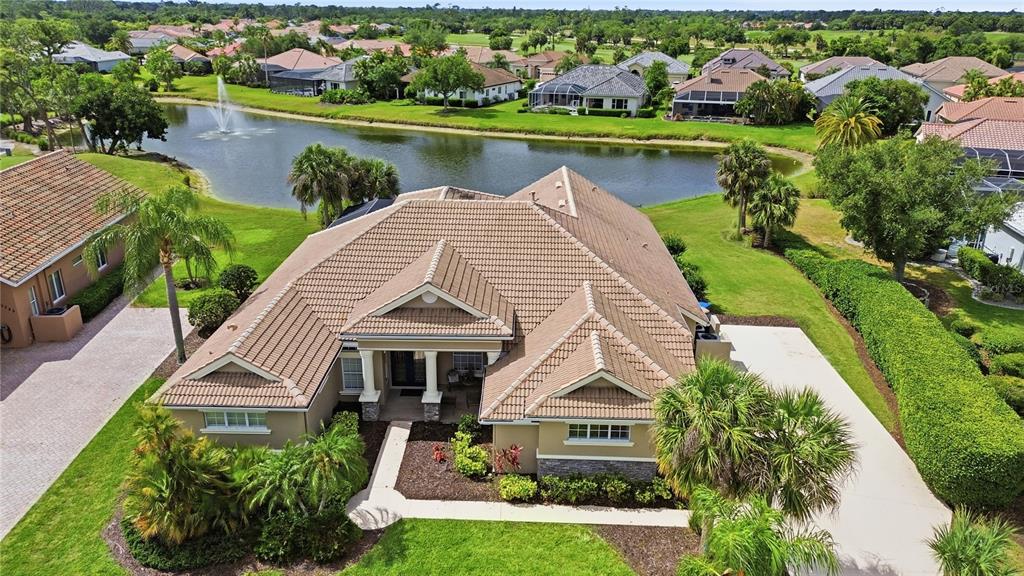 An aerial view of a tan house with a tiled roof next to a pond — 5291 WHITE IBIS DRIVE, NORTH PORT, FL