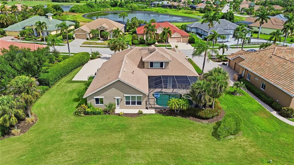 An aerial view of a suburban house with a screened-in pool and a large lawn — 5291 WHITE IBIS DRIVE, NORTH PORT, FL