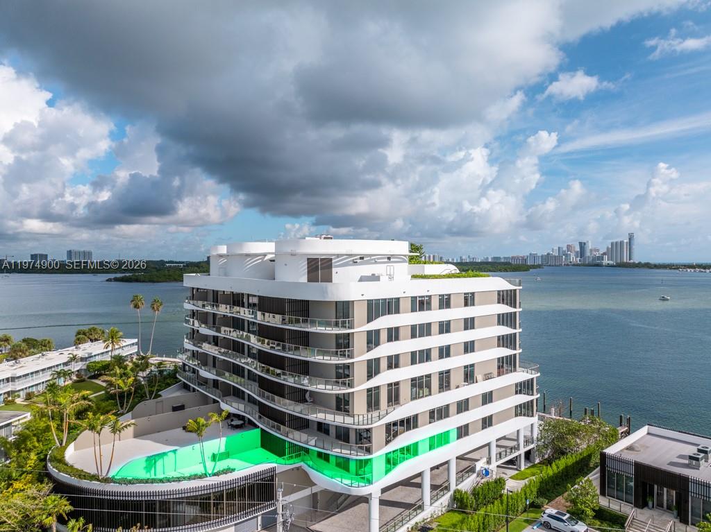 An aerial view of a modern multi-story apartment building with a bright green swimming pool — 1135 103rd # 307, Bay Harbor Islands FL 33154, BAY HARBOR ISLANDS, FL