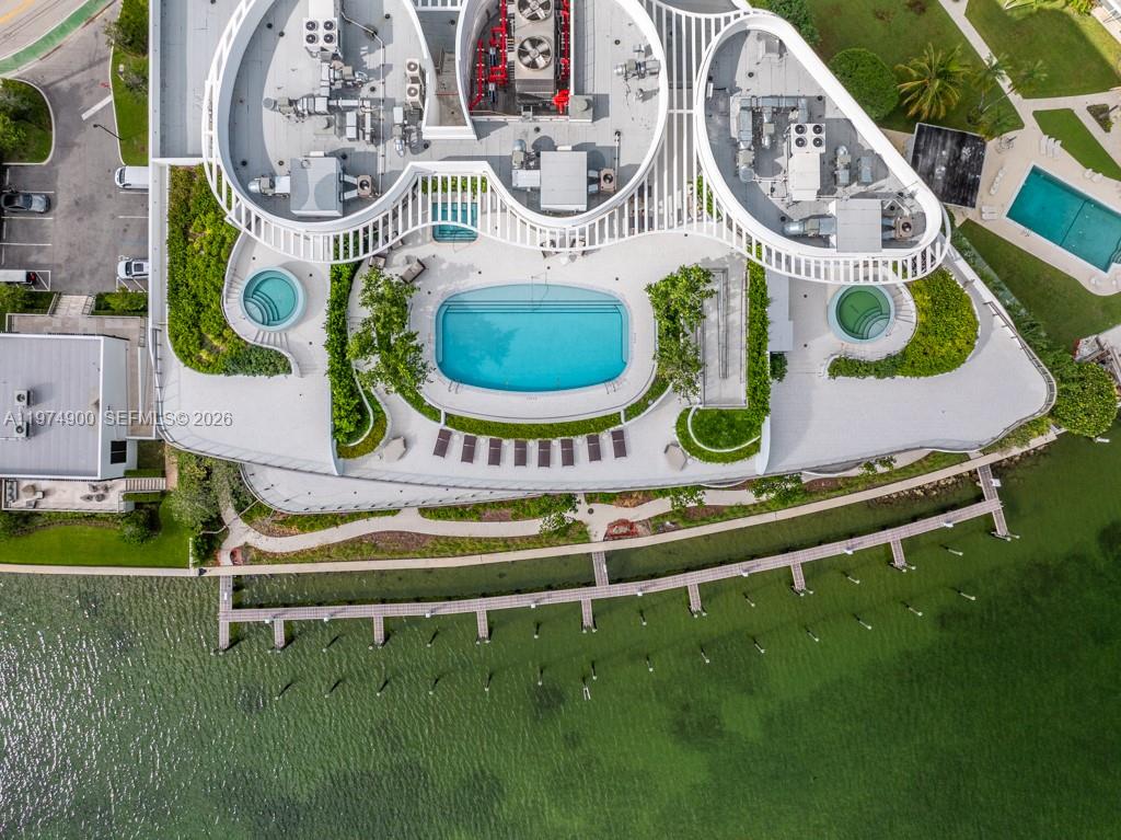 An aerial view shows a modern building with a pool deck, landscaping, and a dock — 1135 103rd # 307, Bay Harbor Islands FL 33154, BAY HARBOR ISLANDS, FL